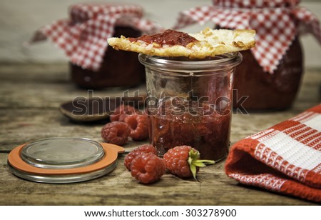 Handmade raspberry jam in a jar with almond cake on top