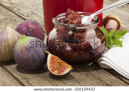 jar of pickled figs in port wine, fresh fruit and  port bottle on rustic table