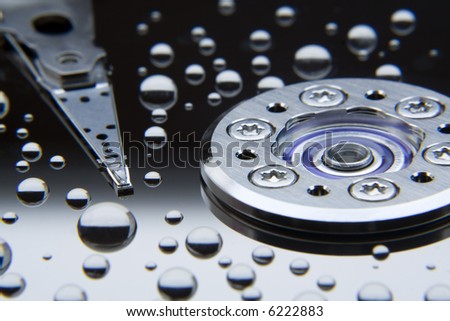 water droplets on the reflective surface of a hard disk with read/write head, macro