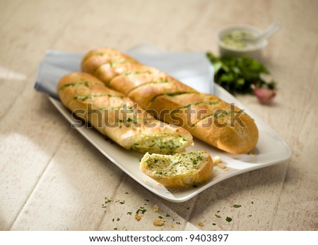 two small baguettes filled with herb butter on white plate