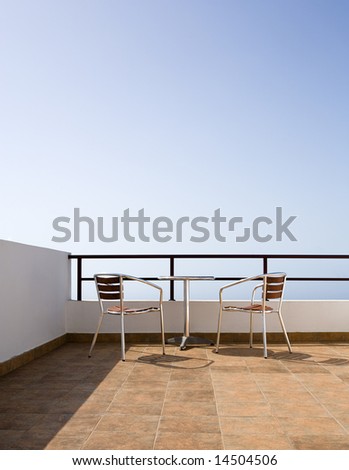 balcony with two wood/aluminum chairs and table, sky background