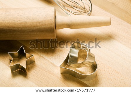 cookie cutters, whisker and rolling pin on wooden board
