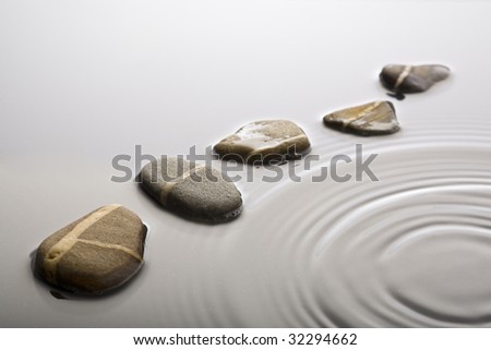 striped pebbles forming a curve in rippled water surface