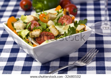 fresh and healthy mixed salad with croutons in square bowl on table, shallow depth of field