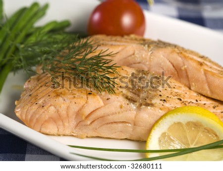 two fillets of salmon garnished with lemon slice, dill and tomato