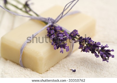 handmade lavender soap and blossoms bundled with purple ribbon on towel, shallow depth of field