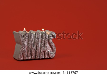 the word XMAS as silver glimmering candle on red background