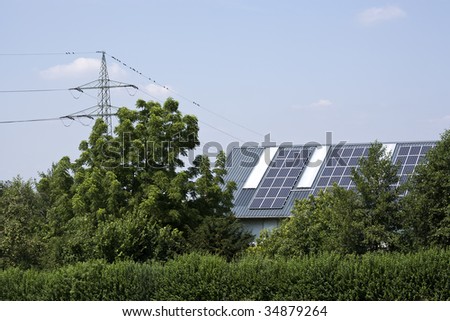 solar heating and electricity panels on roof, trees in foreground, power line in background