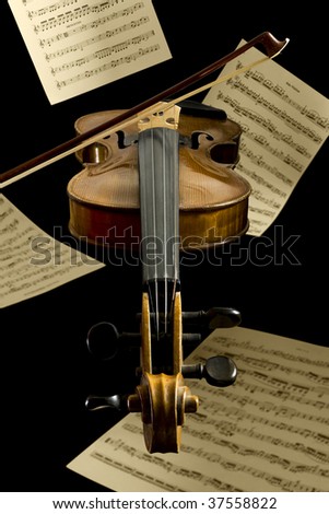 violin, bow and notation sheets by Mozart and Beethoven floating in front of black background