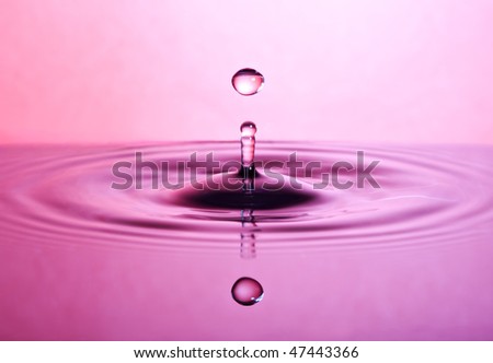 single drop jumping up from water surface, pink light