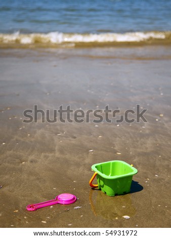 pink toy shovel and green bucket at the beach
