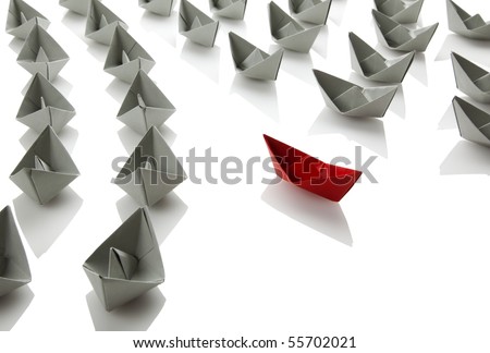 gray paper boats sailing in one direction, red boat to the other, isolated on white