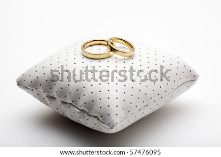 stock photo golden wedding rings on small white leather cushion