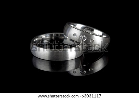 stock photo silver or titanium wedding rings reflected on black background