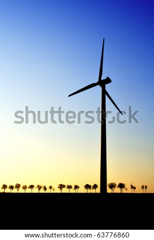 wind turbine at dawn, trees in background