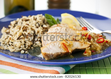stripes of turkey breast with lemon and chili pepper sauce arranged with wild rice, very shallow depth of field
