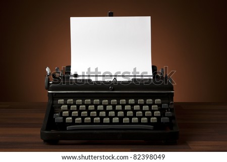 old portable typewriter with blank paper on desk