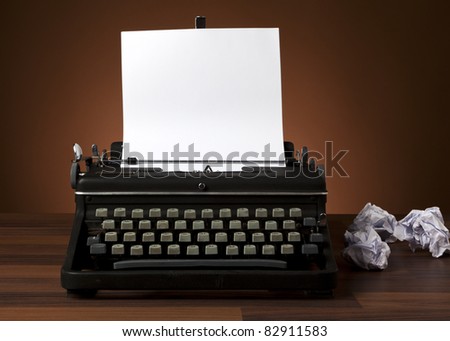 typewriter with blank paper, crumpled pages on desk
