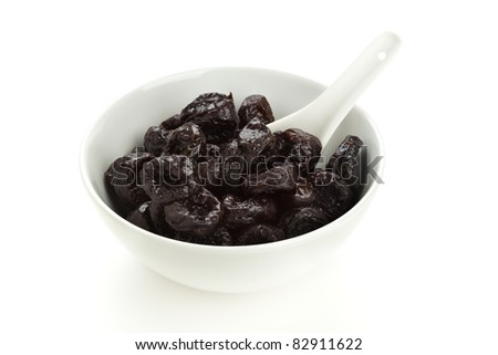 dried prunes in white bowl with china spoon