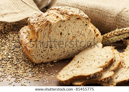 whole grain bread with slices, burlap bags with grain in background