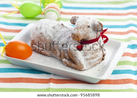 easter lamb cake with powdered sugar and red heart on collar, easter eggs aside