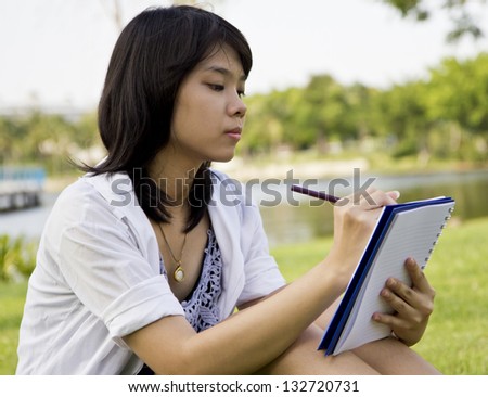 Girl writing a book in the park, park in thailand