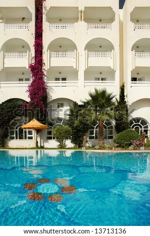 Luxury exclusive hotel swimming pool, with palms and umbrellas