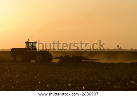 Silhouette of farmer in tractor tilling his land in late autumn after the harvest.  In Logan County near Lincoln, Illinois in the Midwest United States.
