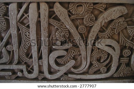 Detailed carved Arabic script from wall in La Alhambra, a moorish mosque, palace and fortress complex in Granada, Spain.