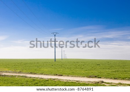 Transmission towers and power lines on a flat landscape in central Spain.