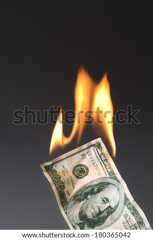 One hundred dollar bill on fire with black background