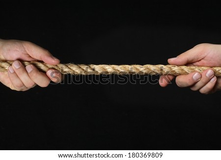 hands pulling piece of rope on black background