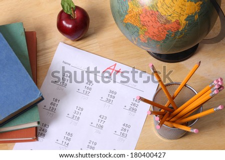 School education still life with books, globe, apple, pencils and a paper with A+ grade