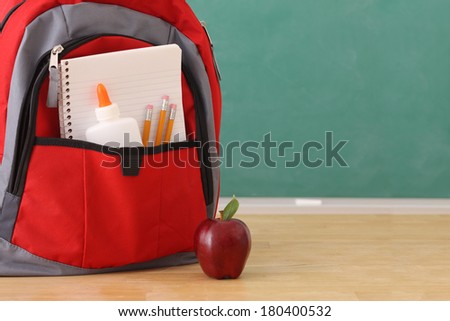 School education still life, backpack full of school supplies and red apple