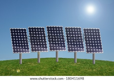 Row of solar panels in grass with blue sky and sun