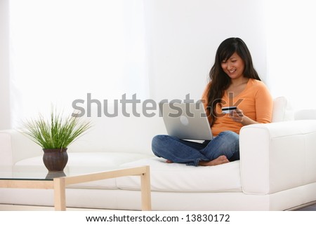 Woman sitting on couch with laptop and credit card