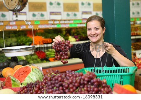Woman at grocery store picking up grapes