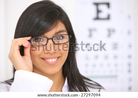 Young woman with glasses, eye chart in background