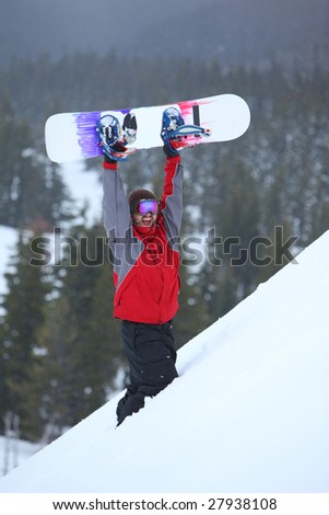 Snowboarder holding up snowboard