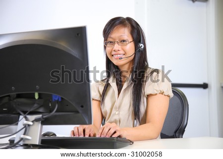 Asian woman with headset working at computer