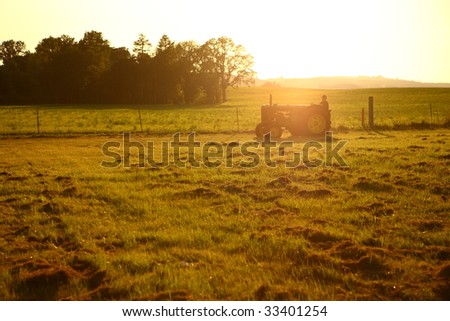 Tractor in field at sunset