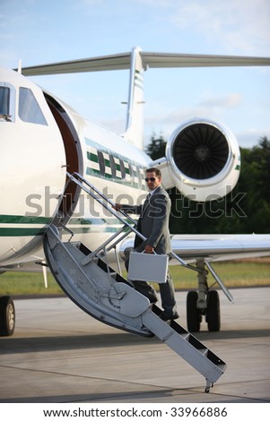 Businessman standing on stairs to private jet