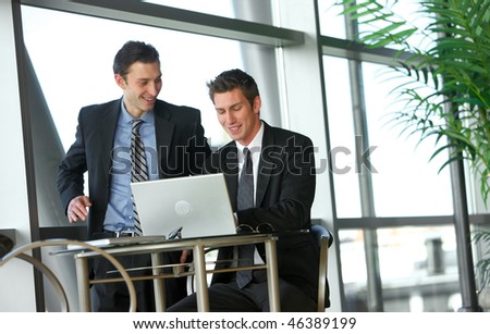 Two young businessmen looking at laptop computer
