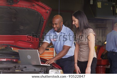Auto shop mechanic working on laptop computer with customer