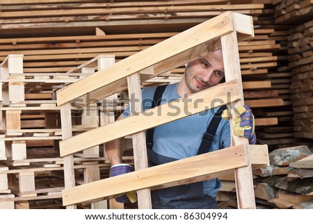 Man moving wood pallets in a warehouse.