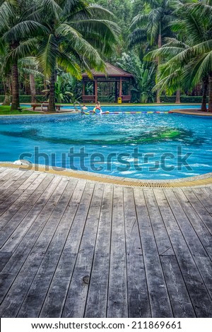 Luxury swimming pool with hut and wooden pool deck in garden of resort