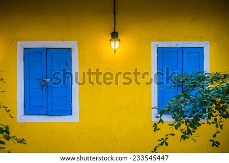 The wall lamp and locked blue windows of yellow house