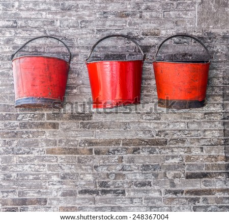 The old red metal buckets for decoration on the brick wall