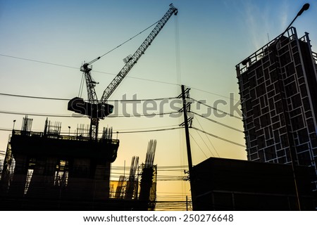 Building construction industrial with construction cranes silhouette at sunset
