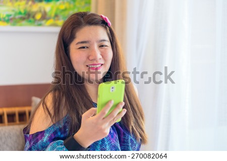 Happy asian woman is playing and chatting on her mobile phone to communication with another people